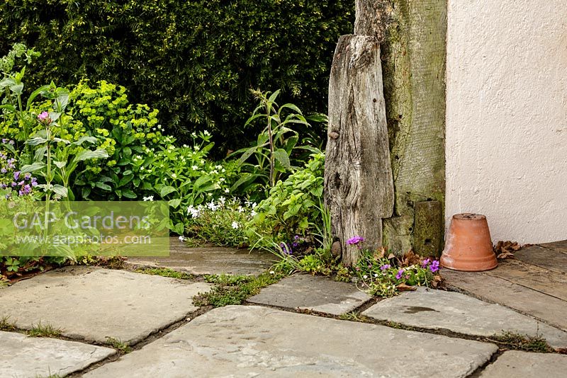 Rustic paving, wooden post, upturned terracotta pot and naturalistic planting - Macmillan Legacy Garden - RHS Malvern Spring Show 2016. Designer: Mark Eveleigh, Sponsor: Macmillan Cancer Support