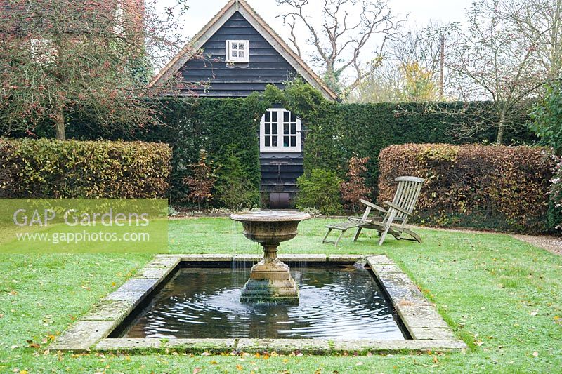 Formal garden 'room' framed by yew and hornbeam hedges with a rectangular pool at its centre featuring an overflowing urn to introduce movement.