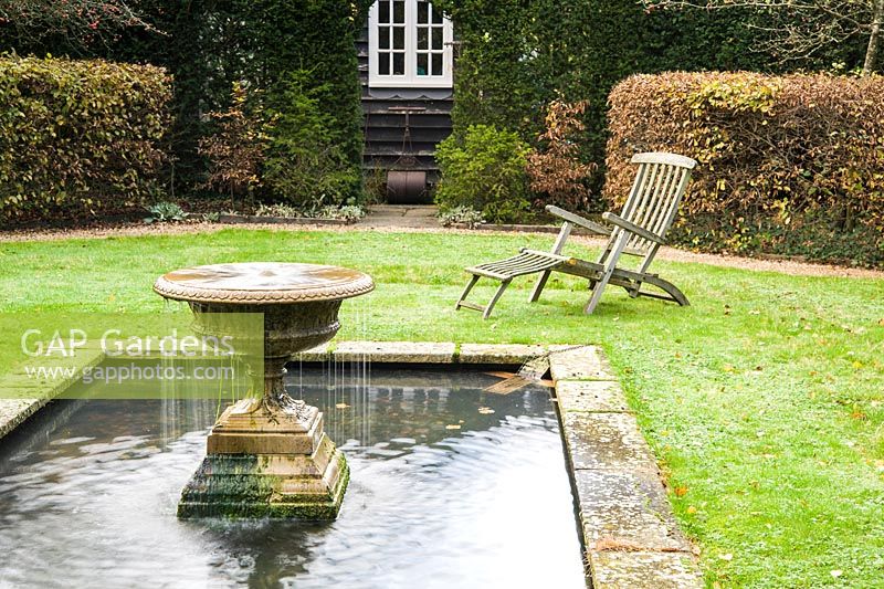 Formal garden 'room' framed by yew and hornbeam hedges with a rectangular pool at its centre featuring an overflowing urn to introduce movement.