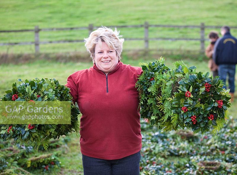 Woman holding bunches of mistletoe and holly at auction