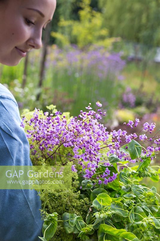 Young girl carrying bundle of cut flowers. Euphorbia, Alchemilla mollis and Thalictrum