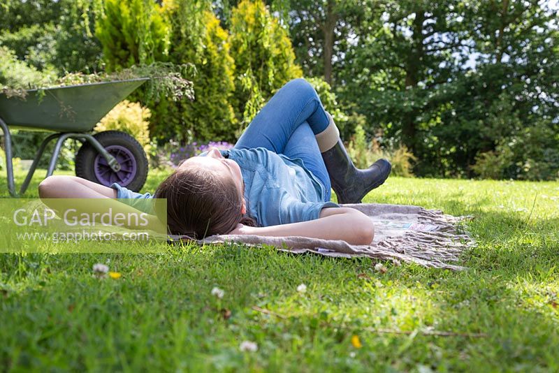 Young girl laying on a rug in the garden relaxing