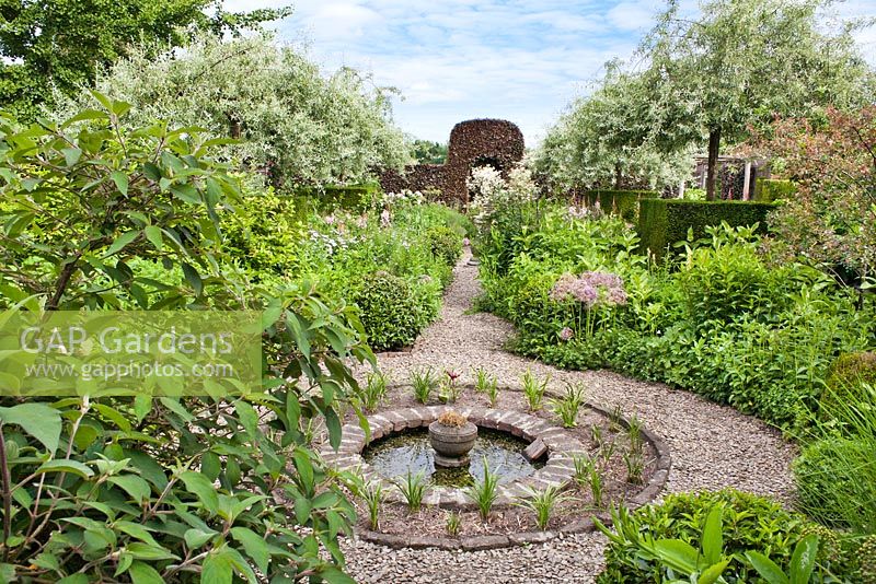 Summer borders in formal garden with small circular pond. Frank Thuyls garden.