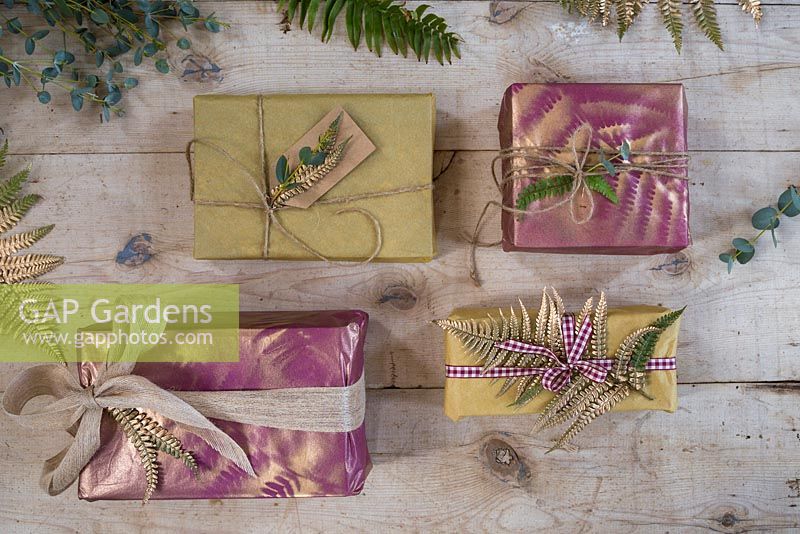 A variety of presents decorated with natural Fern and Eucalyptus foliage and spray painted imprints