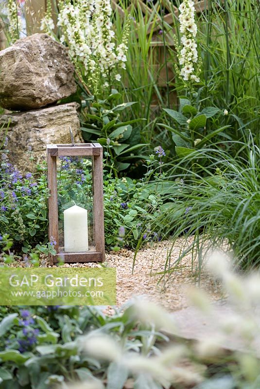 A candle on a gravel bed with Pennisetum villosum and Nepeta x fassenii- The Drought Garden, RHS Hampton Court Palace Flower Show 2016.