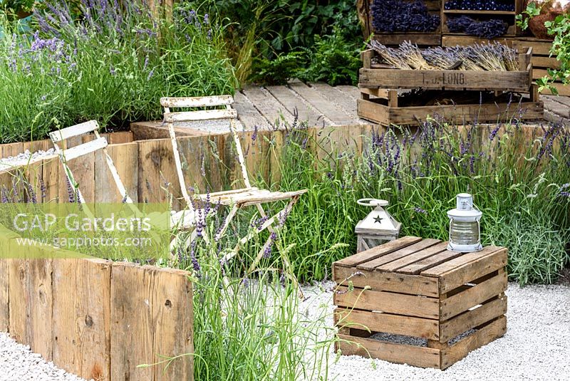 Bistro chairs with wooden crate for a table, surrounded by Lavender.  Hampton Court Flower Show 2016. 'The Lavender Garden' designed by Paula Napper, Sara Warren, Donna King