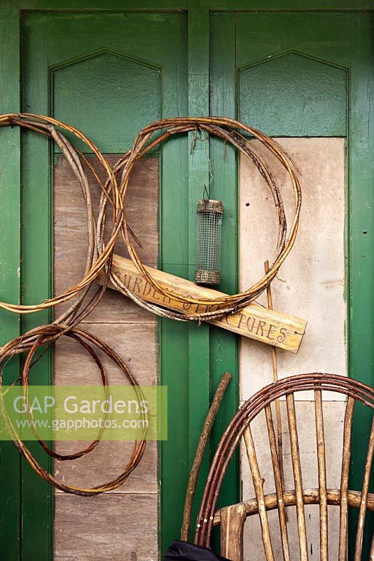 Woven willow plant supports hanging on green painted shed - June