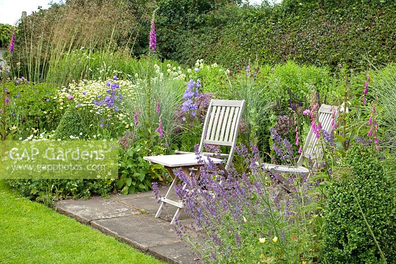 Seating area within an herbaceous border at Bolham Manor, Nottinghamshire in June