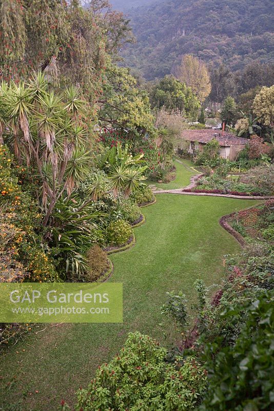 Aerial view of gardens with borders, terracotta roofed house and tree covered hills beyond - Lake Atitlan Hotel, Guatemala