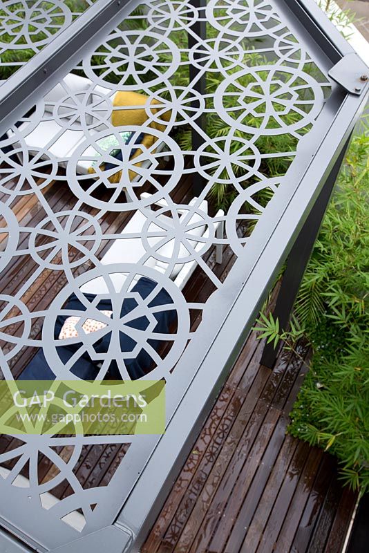 Overhead view of grey metal laser cut pergola roof showing the deck and seating area below.