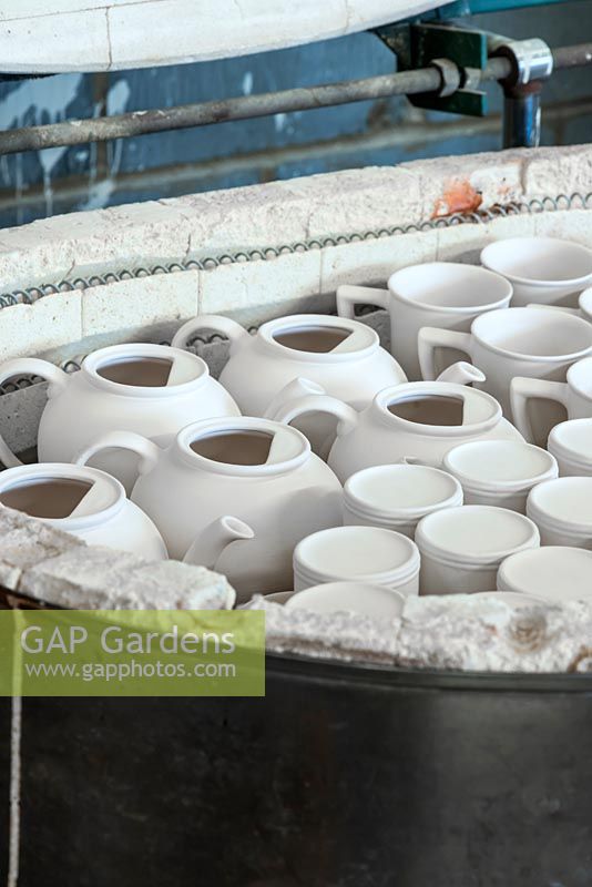 Cooling in a kiln, unglazed teapots and mugs known as 'biscuitware', after biscuit firing which hardens the clay ready for hand decoration.