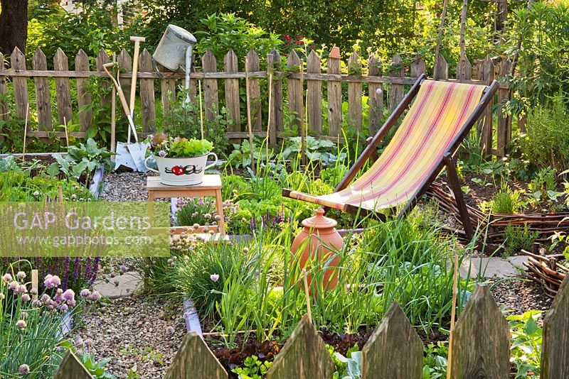 Deckchair in mixed borders of vegetables and herbs. 