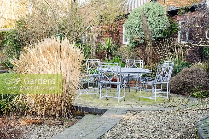 Seating area at the back of the house surrounded by planting including grasses such as Miscanthus sinensis 'Yakushima Dwarf' and sedums. Windy Ridge, Little Wenlock, Shropshire, UK
