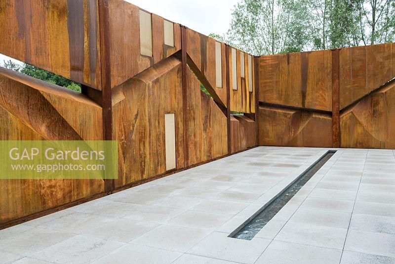 Rusting steel walls, paving and rill water channel in the IQ Quarry Garden, Best in Show at RHS Chatsworth Flower Show 2017. Designer: Paul Hervey-Brookes