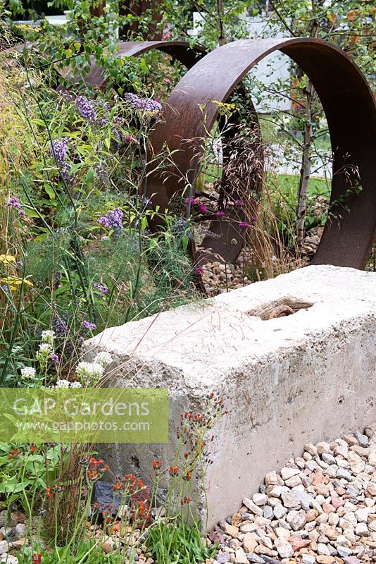 Self-seeded perennials surround rusted steel and concrete structures, including Buddleja davidii, Foeniculum vulgare and Pilosella aurantiaca -  Brownfield Metamorphosis, RHS Hampton Court Palace Flower Show 2017