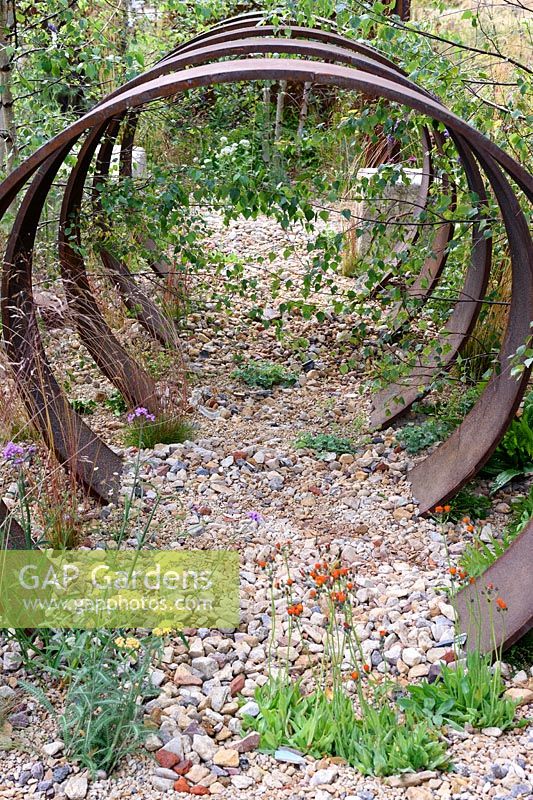 Brownfield - Metamorposis. Repeating rusted steel hoops buried incrushed stone rubble, Design: Martyn Wilson. Sponsors: St. Modwen. RHS Hampton Court Palace Flower Show 2017