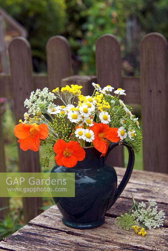 Summer arrangement of orange, yellow and white flowers on wooden table