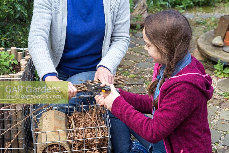 Child cutting down sticks to fit into container