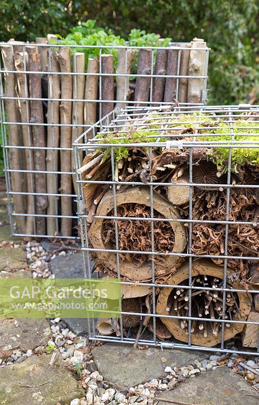 Insect hotel made from natural materials inside gabion container
