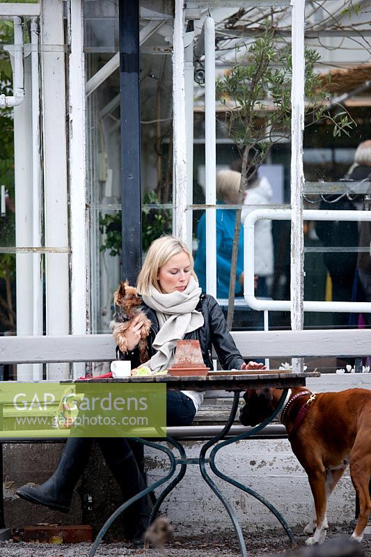 Woman sitting at table with pet dog. Rosendals Tratgard. Stockholm. Sweden