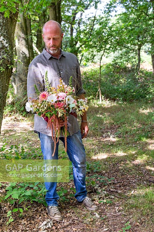 Man holding floral arrangement with mix of flowers and grasses