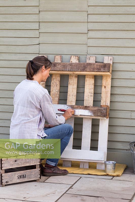 Woman painting pallet with white paint