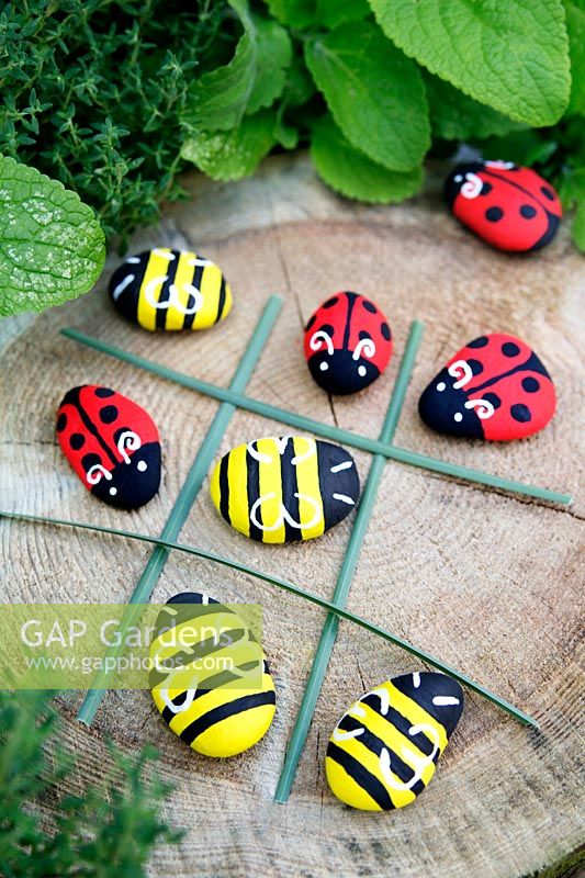Garden craft making painted Bumble bees and Ladybirds with stones. Long grasses laid out to make a noughts and crosses board
