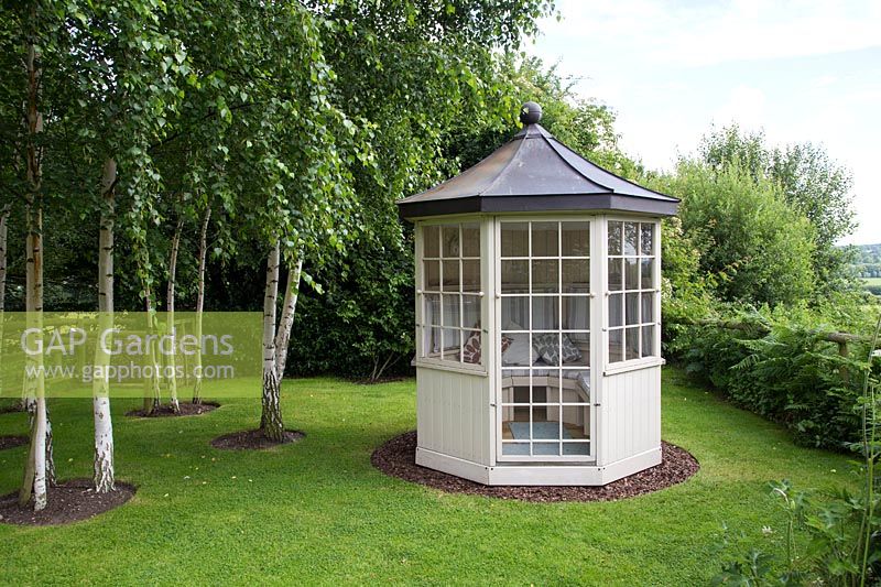 A rotatable Summer House located at the end of the garden next to a group of Birch trees