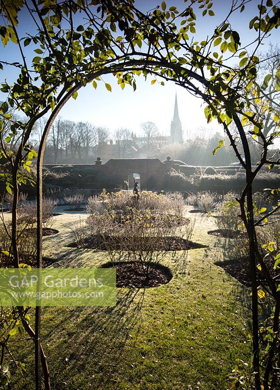 View through iron arch to The Rose Garden with a statue of an archer. Bridge End Garden, Saffron Walden, Essex