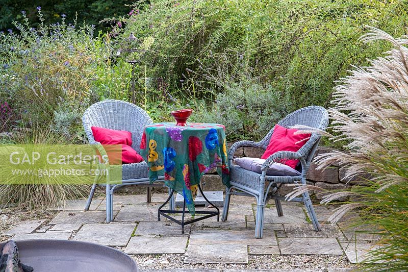 Seating area on patio. Plants include Caryopteris  glandonensi and Miscanthus sinensis
