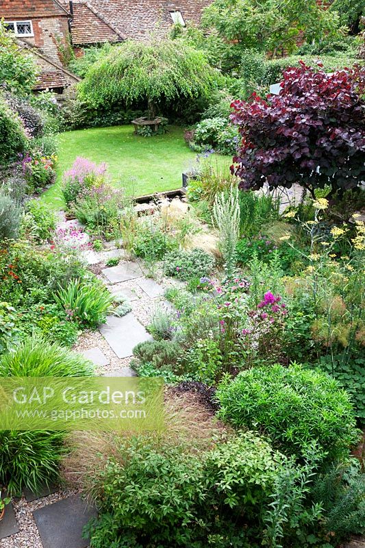 Overhead view of a small low maintenance modern cottage garden. York stone and gravel pathway meander through planting with Stipa tenuissima, Hakonechloa macra 'Aureola', Stipa arundinacea, Verbena bonariensis, Thyme, Verbascum, Fennel, Lychnis coronaria, Cercis canadensis 'Forest Pansy' to the weeping Birch - Betula pendula 'Youngii'.