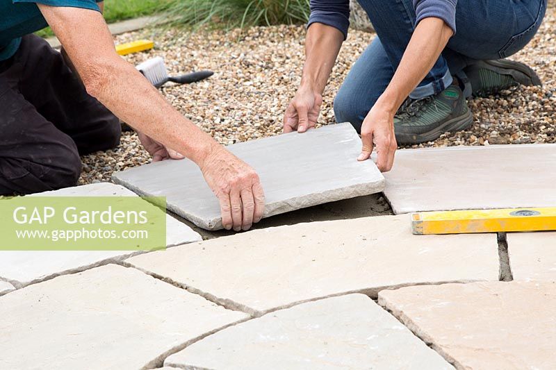 Woman and Man working together laying patio slabs 
