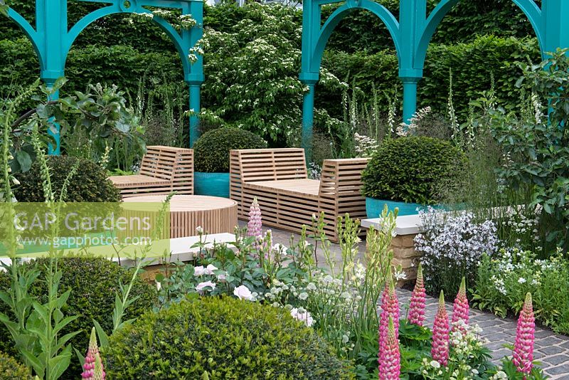 Iron structures, old apple trees and rich planting of Lupins, Foxgloves, Roses and Astrantias. Furniture by Jonathan Stockton - The Sir Simon Milton Foundation Garden: '500 years of Covent Garden' - RHS Chelsea Flower Show 2017 - Designer: Lee Bestall - Sponsor: Capco Covent Garden