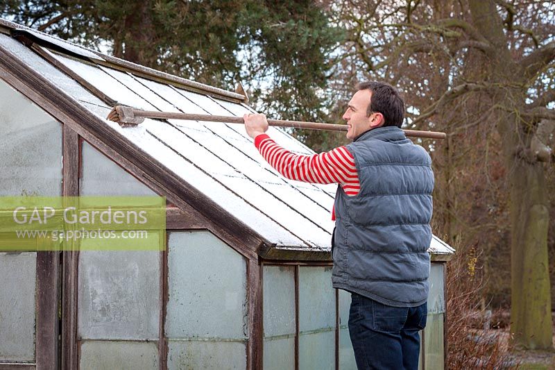 Brushing snow off a greenhouse roof