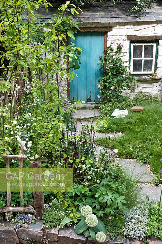 A Postcard from Wales by Kati Crome and Maggie Hughes. Traditional cottage with stone path, lawn and border with perennials including Astrantia, Nectaroscordum, Aquilegia, Allium, Campanula and Amelanchier. Chelsea Flower Show 2011