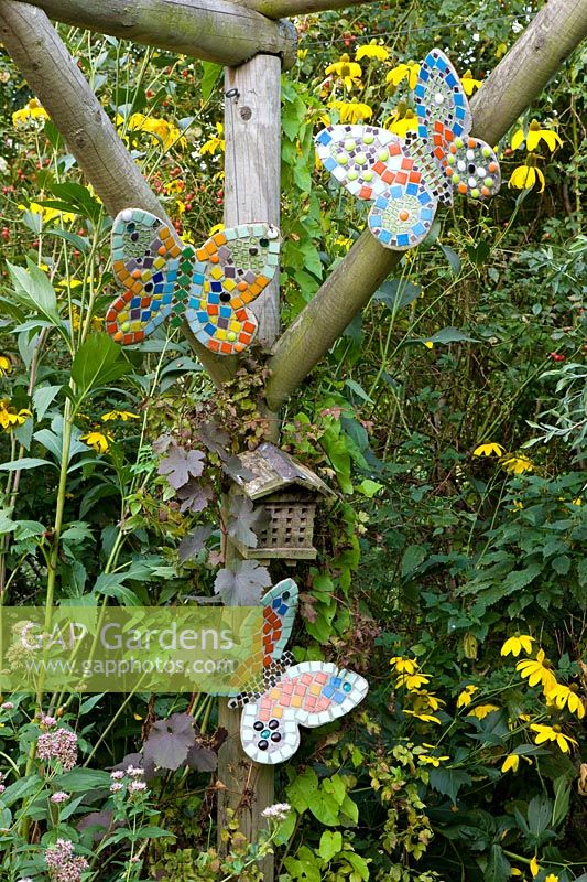 Mosaic 'butterflies' and insect house on wooden pergola