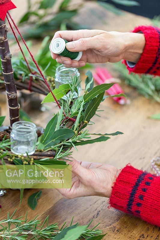 Close up detail of using florist wire to secure Rosemary and Bay foliage to natural wreath base