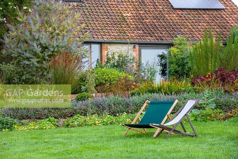 Special Plants ( Derry Watkin's garden ), Bath, UK. Late summer, two deck chairs on lawn