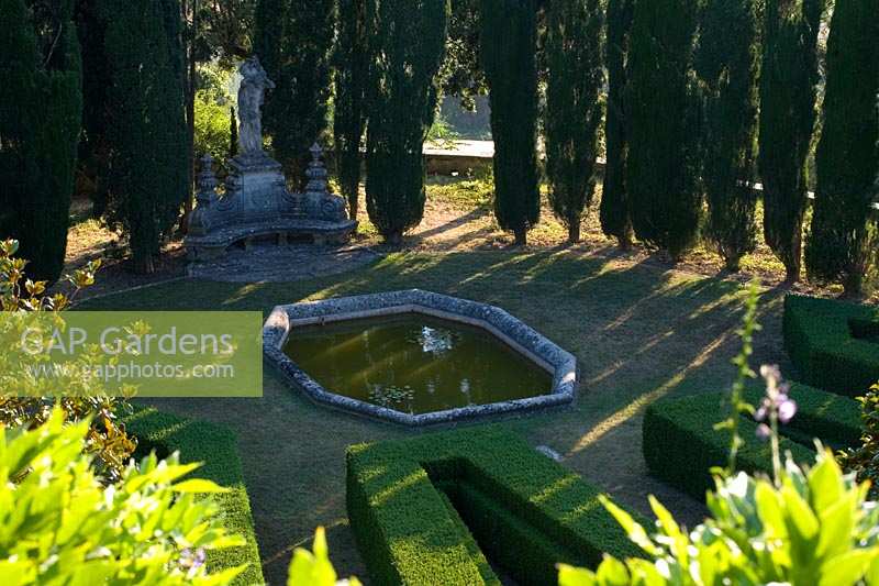 Villa La Foce, Tuscany, Italy. Large garden with topiary clipped Box hedging and views across the Tuscan countryside, shady pond on lower terrace