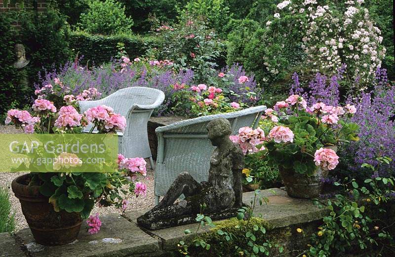 Frith Lodge Sussex Terrace patio with wicker chairs and containers Pelargonium Dolche Vita catmint and statue