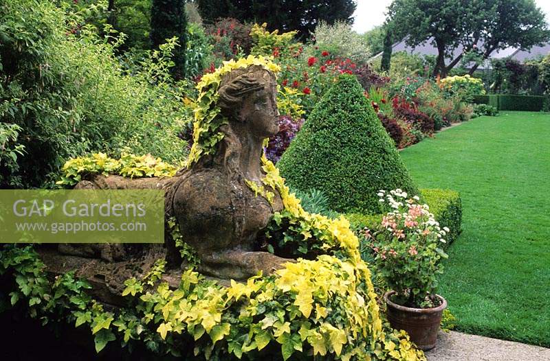 The Dillon Garden Dublin Ireland large town suburban garden stone Sphinx statue covered with Hedera helix Buttercup and pyramid