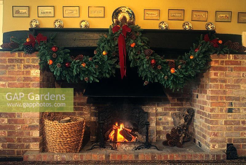 Coates Manor Sussex Christmas decorations fireplace with garland and open fire winter December