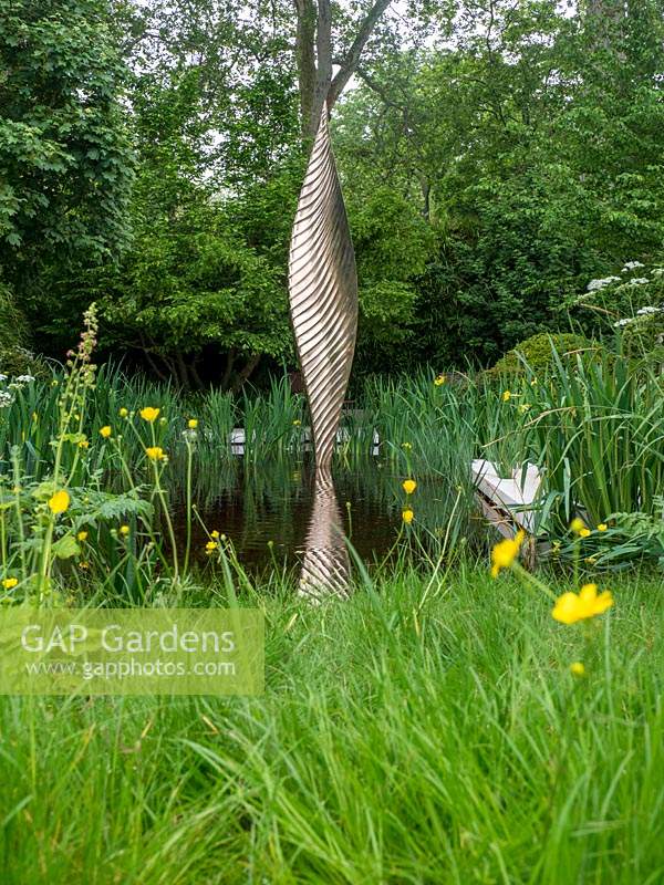 The Savills and David Harber Garden is a green garden depicting a sustainable woodland clearing, with sculpture and central water feature. Designed by Andrew Duff, Sponsored by David Harber Savills, RHS Chelsea Flower Show, 2019.
