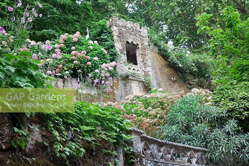 Tower above Chapels Tunnel  seen from below with Hydrangeas and Japanese Anemones. Sintra, Portugal.