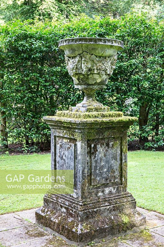 A stone pillar and urn with antique carving on lawn at Newby Hall and Gardens, Yorkshire.
