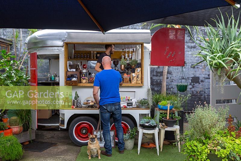 A man being served coffee by a barista in a pop up converted horse float cafe, Australia. 
