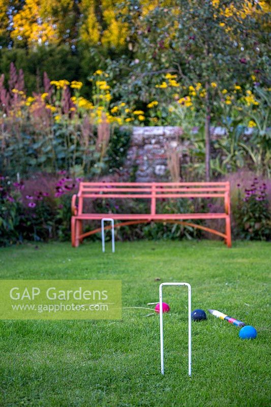 Garden bench and croquet set on garden lawn. 