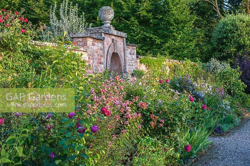 Walled kitchen garden Lilium speciosum 'Black Beauty' and Clematis viticella 'Emilia Plater' - Morton Hall Gardens, Worcestershire