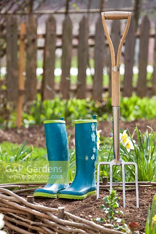 Boots and digging fork on a raised bed
