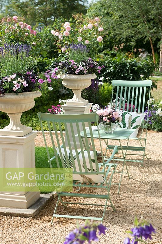 Green table and chairs in classic garden at RHS Hampton Court Palace Flower Show 2015.

